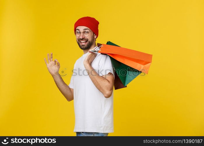 Photo of happy guy, holding shopping bags, isolated over yellow background.. Photo of happy guy, holding shopping bags, isolated over yellow background