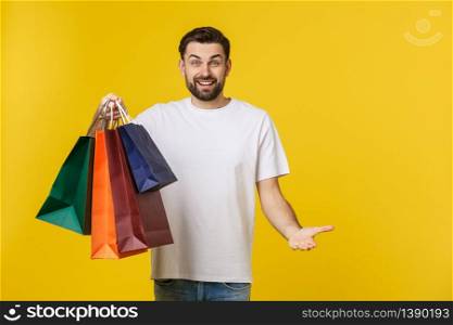 Photo of happy guy, holding shopping bags, isolated over yellow background.. Photo of happy guy, holding shopping bags, isolated over yellow background