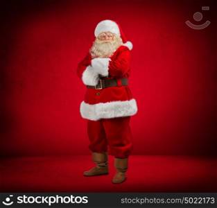 Photo of happy Santa Claus looking at camera on red background. Full length portrait