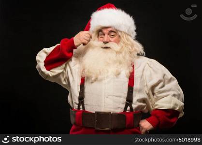 Photo of happy Santa Claus touching mustache and looking at camera on dark background