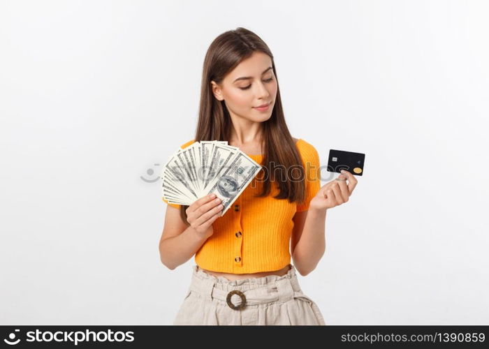 Photo of happy young woman standing isolated over grey background. Looking aside holding money and credit card.. Photo of happy young woman standing isolated over grey background. Looking aside holding money and credit card