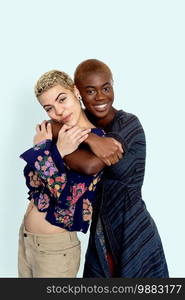 Photo of joyful ladies embrace and enjoy togetherness, being of different of races, dressed in casual jumpers, isolated over white background. Diverse women laugh happily, have fun together.