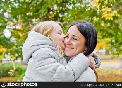 Photo of kissing mother and daughter in autumn