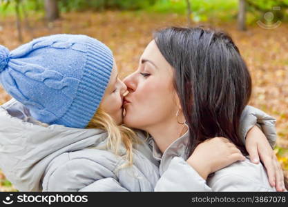 Photo of kissing mother and daughter in autumn