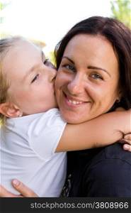 Photo of kissing mother and daughter in summer