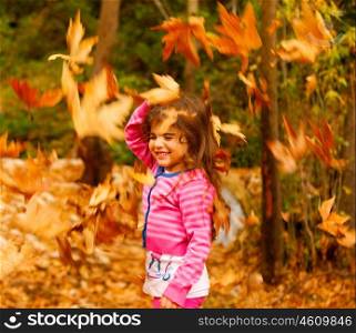 Photo of little cute girl playing in autumn park, adorable sweet kid throwing up old dry foliage, cheerful small female child playing outdoors, nice toddler laughing with closed eyes&#xA;