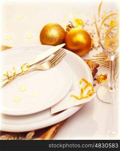Photo of luxury Christmas table decoration, white plate with knife and fork, glass for wine, traditional New Year holiday table setting with golden bubble decor, happy Christmastime celebration