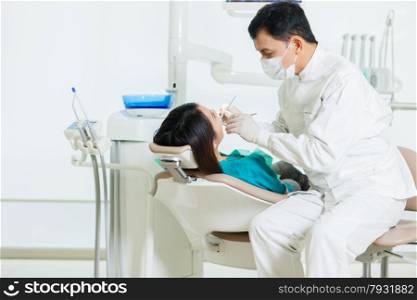 photo of male asian dentist diong a dental check up to a young asian woman in a dentist office