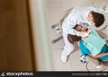 photo of male asian dentist doing his job on a young asian woman