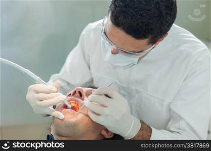 photo of male dentist doing a hygienical treatment to a 40 years old patient
