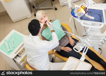 photo of male dentist doing his job on a caucasian young patient