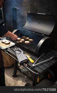 Photo of man cooking marbled meat on barbecue for burgers