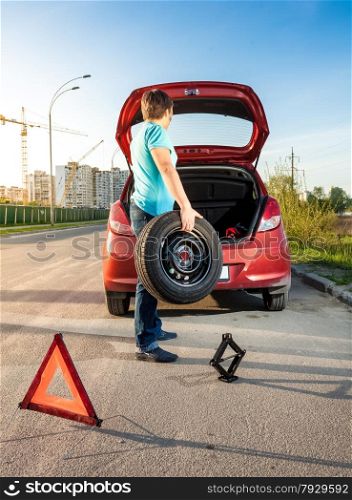 Photo of man taking spare wheel out of trunk