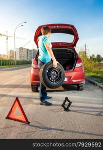 Photo of man taking spare wheel out of trunk