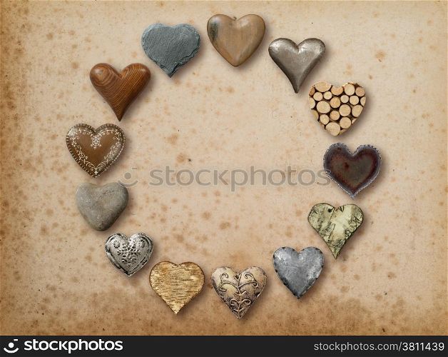 Photo of metal, wood and stone heart-shaped things organized in a circle over vintage paper background.&#xA;
