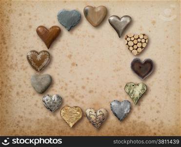 Photo of metal, wood and stone heart-shaped things organized in a circle over vintage paper background.&#xA;
