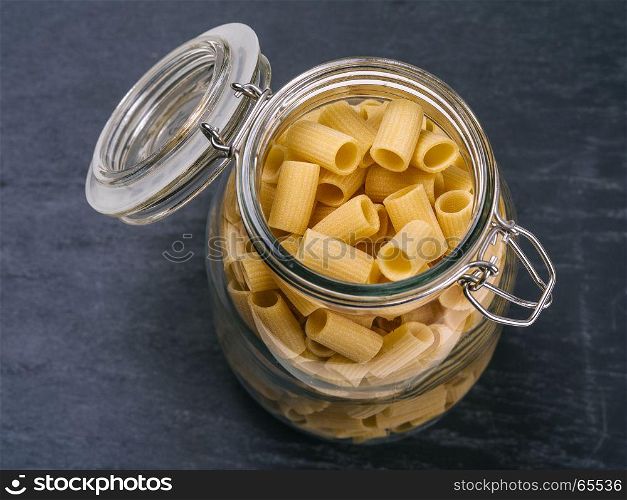 Photo of Mezzi Rigatoni in an open jar on top of a slate background.