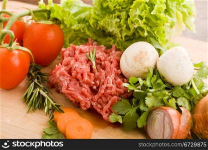 photo of minced meat with vegetables on a wooden chopping board