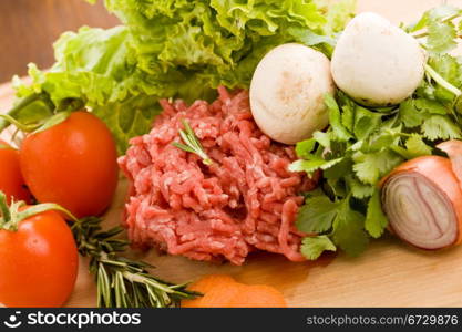 photo of minced meat with vegetables on a wooden chopping board