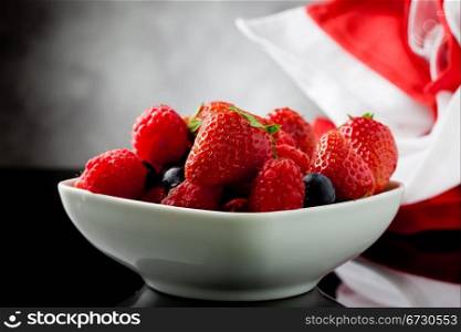 photo of mixed fresh berries on grey lighted background