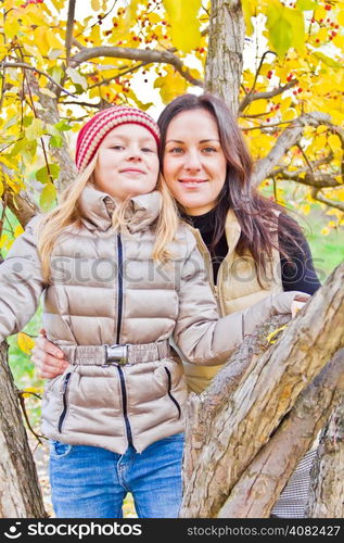 Photo of mother and daughter in autumn sitting on tree