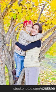 Photo of mother and daughter in autumn sitting on tree