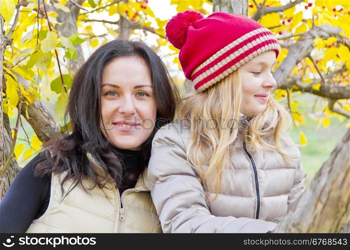 Photo of mother and daughter on spreading tree in autumn