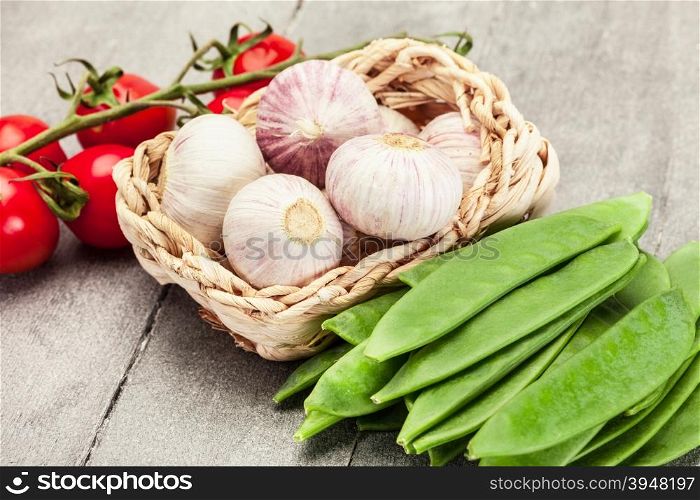 Photo of of garlic, tomatoes and sugar peas over wooden table