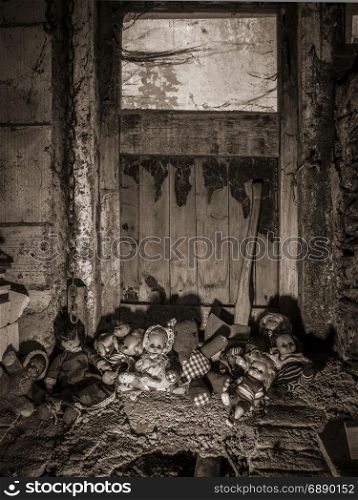Photo of old dolls and an axe resting against an old barn door covered in spiderwebs and dust.