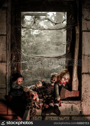 Photo of old dolls and an axe resting on an old window ledge covered in spiderwebs and dust.