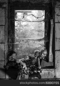 Photo of old dolls and an axe resting on an old window ledge covered in spiderwebs and dust.