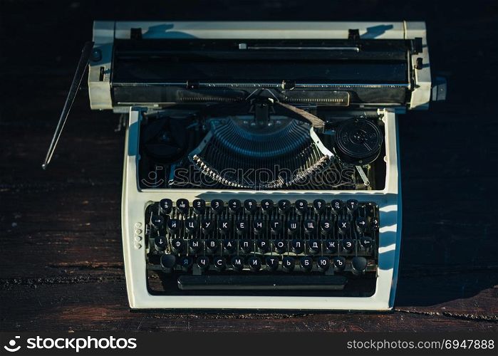 Photo of old typewriter on wooden table in sunset light, retro look.. Photo of old typewriter on wooden table in sunset light, retro look