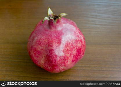 Photo of one pomegranate on brown wooden background