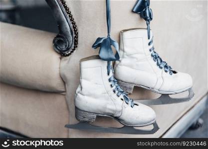 Photo of pair worn winter leather white skates for figure skating with shoelaces hang on ribbon. Used women`s skates of professional skater or ice hockey player