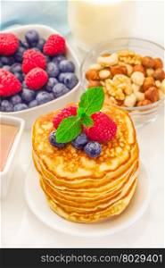 Photo of pancakes with berries over wooden table