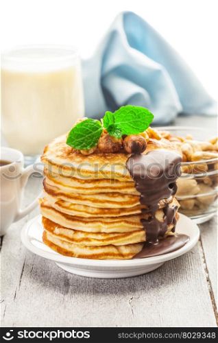 Photo of pancakes with chocolate and nuts over wooden table