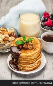 Photo of pancakes with chocolate and nuts over wooden table