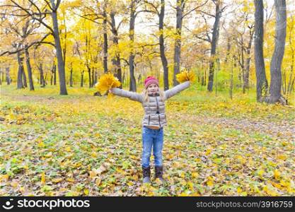 Photo of playing girl with two bouquets of sheets in autumn