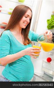 Photo of pregnant woman pouring orange juice in glass