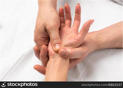 Photo of reception massage hands closeup on white sheets
