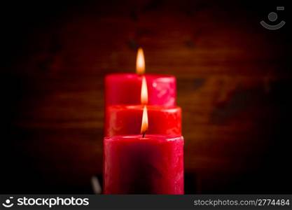 photo of red christmas candles on wooden table highlighted by spot
