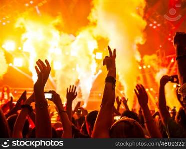 Photo of rock concert, music festival, New Year eve celebration, party in nightclub, dance floor, disco club, many people standing with raised hands up and clapping, happiness and night life concept