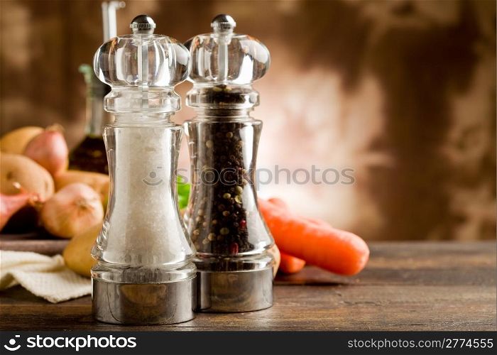photo of salt and pepper mill with ingredients arround on wooden table