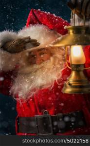 Photo of Santa Claus outdoors under blowing wind and falling snow and looking at camera
