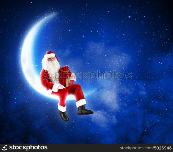 photo of santa claus sitting on the moon. Photo of Santa Claus sitting on shiny moon above winter forest