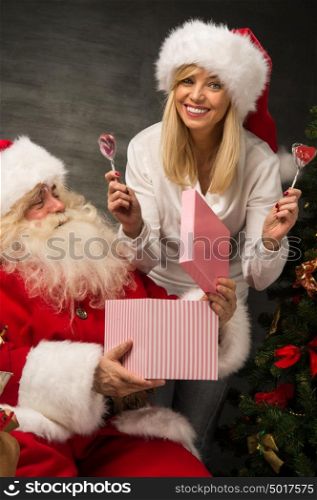 Photo of Santa Claus with his wife surprising and opening Christmas gift at home
