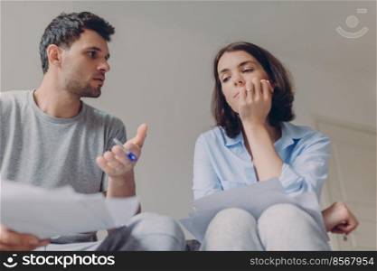 Photo of serious female and male do paperwork together, review bank documents and hold pen, discuss something, look thoughtfully, speak about something, think about future plans, sign contract