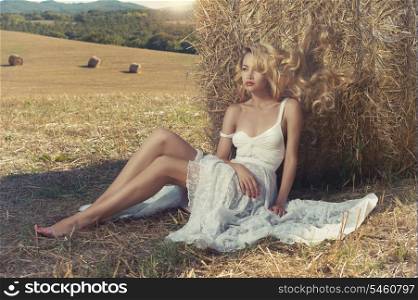 Photo of sexy blonde in a field with haystacks