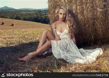 Photo of sexy blonde in a field with haystacks