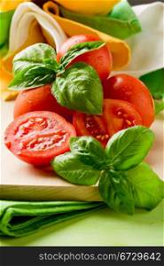 photo of sliced cherry tomatoes with basil on wooden cutting board
